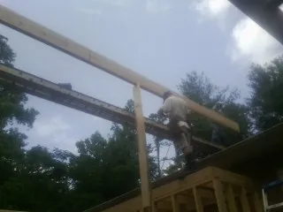 Carpenter setting a ridge beam over a new addition frame — Ice Dam Removal by Roofing Brothers in Cedar Mountain