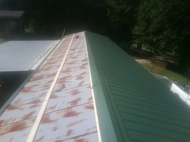Old rusted panels beside newly installed green metal roofing — Wind Damage Roof Repair by Roofing Brothers in Cedar Mountain