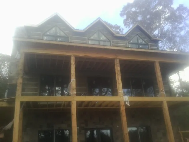 Dormers and porch framing on a large log home under construction — Roof Coating work by our crew in Cedar Mountain