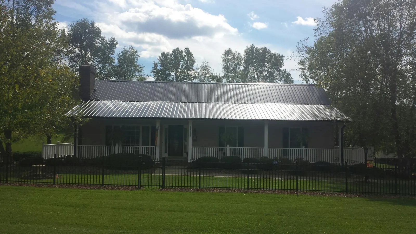 Gray metal roof on a brick ranch with a full width front porch — Gutter Guard Installation work by our crew in Cedar Mountain