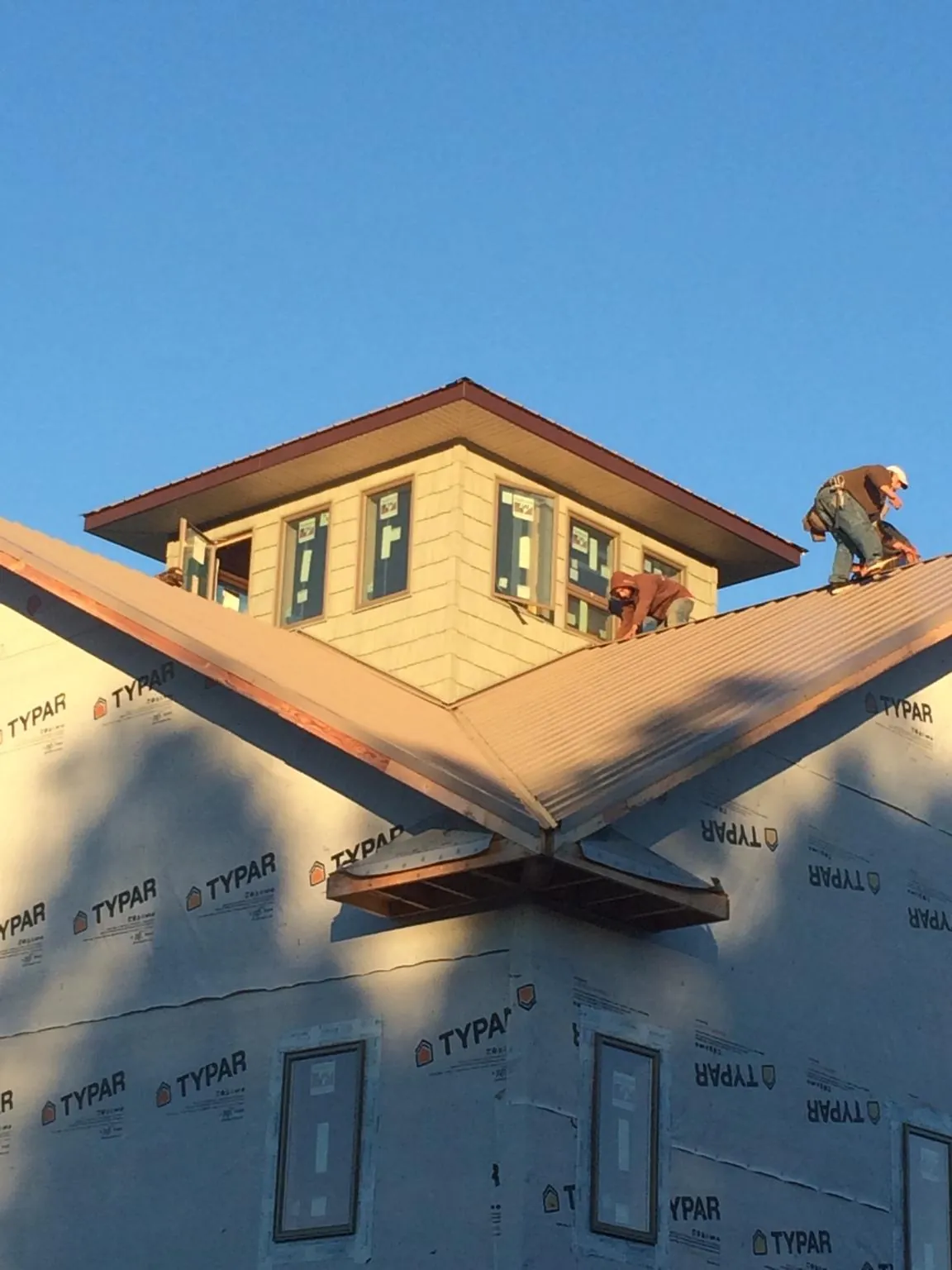 Roofers working around a rooftop cupola on a new metal roof at sunset — Roof Waterproofing in Cedar Mountain by Roofing Brothers